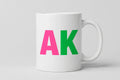 AK Coffee Mug - white ceramic mug with pink and green AK lettering