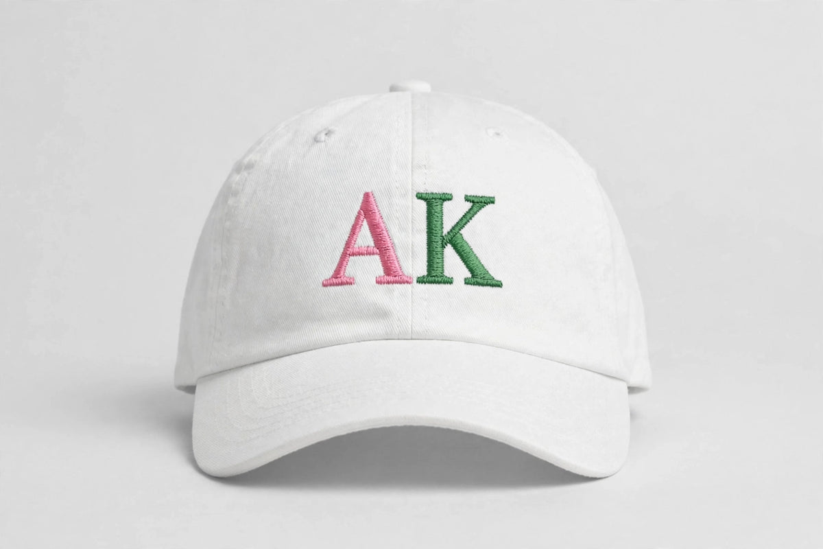 White baseball cap with AK embroidered in pink and green